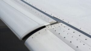 Close-up of corrosion-resistant aerospace rivets installed on a polished aircraft wing.