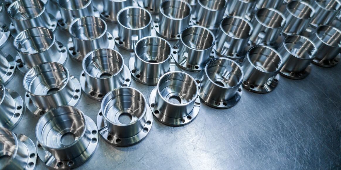 Shiny metal parts after cnc turning, drilling and machining on steel surface with selective focus for industrial background.